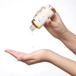 Textura acuosa dorada de Mixsoon Centella Asiatica Essence siendo vertida en mano, essence coreana de absorción rápida con centella