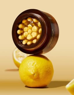 Medicube Deep Vita C Capsule Cream con cápsulas de vitamina C pura sobre fondo de limones, crema coreana antioxidante iluminadora con niacinamida para manchas y tono parejo