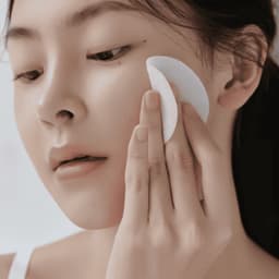 Modelo aplicando Celimax Heartleaf BHA Peeling Pad en rostro, exfoliante coreano en pad con ácido salicílico y centella para renovar textura y iluminar piel opaca
