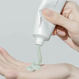 Textura cremosa verde del Celimax Noni Energy Repair Cream saliendo del tubo, crema coreana reparadora con noni de consistencia suave para regenerar piel dañada e irritada
